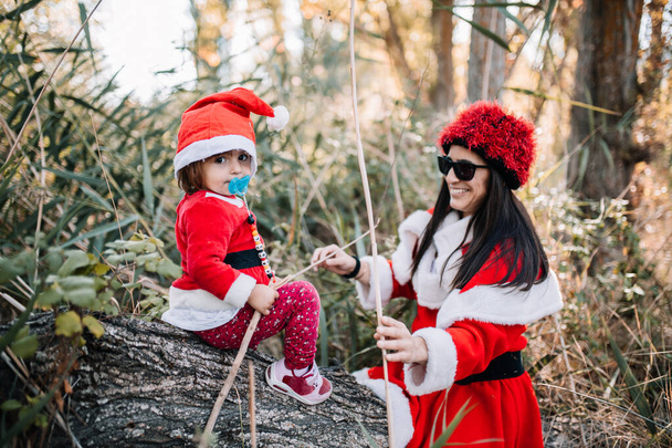 Äiti ja tytär naamioitunut jouluksi metsään
 - Valokuva, kuva