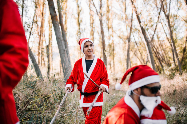 Группа людей, замаскированных под Рождество в лесу
 - Фото, изображение