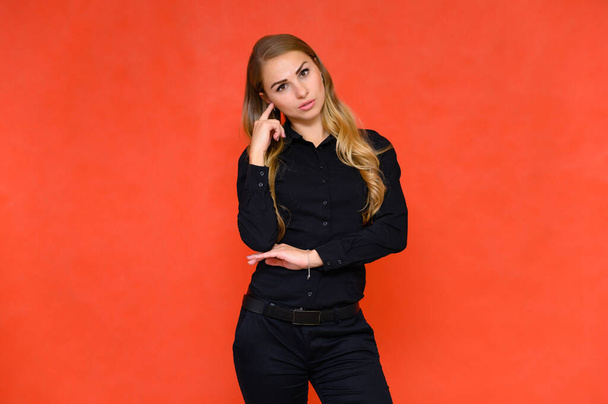 Portrait of a pretty blonde financial secretary girl with long curly hair in a business suit standing in the studio on a red background with emotions in different poses. - Foto, imagen