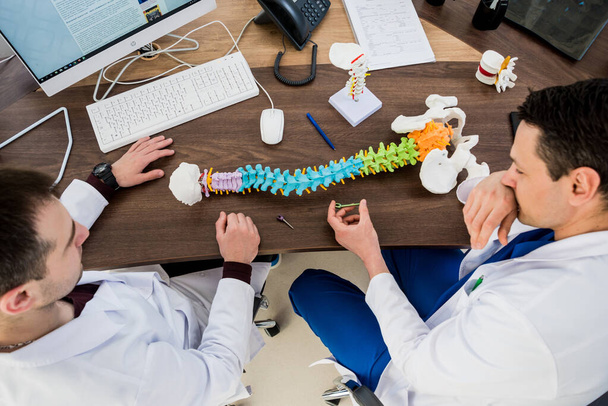 Doutor mostrar parafuso poliaxial no modelo da coluna vertebral. Sistemas de fixação da coluna. Cirurgia da coluna
 - Foto, Imagem