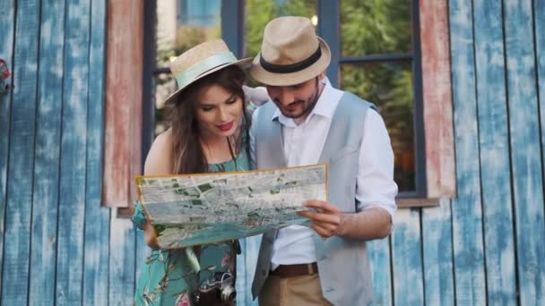 boldog turista utazik. egy férfi és egy nő a kezében egy térképet a város - Felvétel, videó