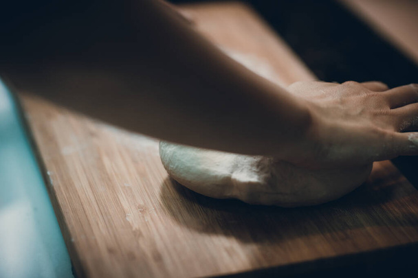 Mulher prepara pele de bolinho, fazendo massa na mesa de madeira
 - Foto, Imagem