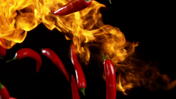 Super zpomalený pohyb létající červené pálivé chilli papričky v ohni s rychlým ramping efektem. Natočeno na vysokorychlostní kameře, 1000 fps - Záběry, video