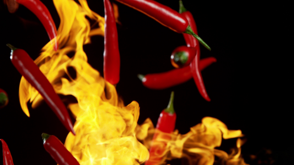 Super zpomalený pohyb létající červené pálivé chilli papričky v ohni s rychlým ramping efektem. Natočeno na vysokorychlostní kameře, 1000 fps - Záběry, video