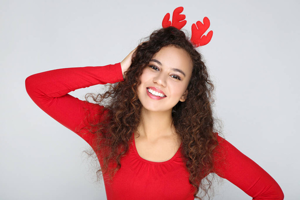 Beautiful american woman in red horns on grey background - Foto, Bild