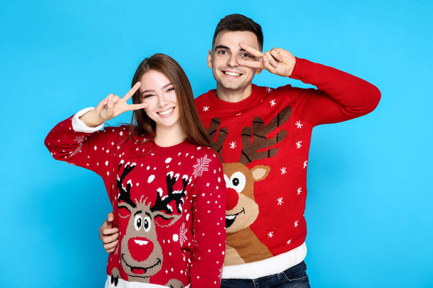 Beautiful man and woman in christmas sweaters on blue background - Фото, изображение