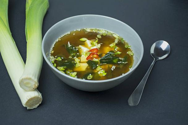 Miso soup with tofu and herbs. Asian food. Dark background. Space for text. - Photo, Image