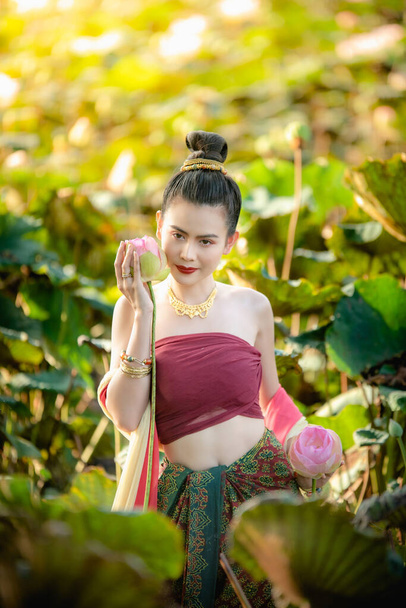 Asian woman collecting lotus flowers and she wear Traditional Thai dresses - Photo, Image