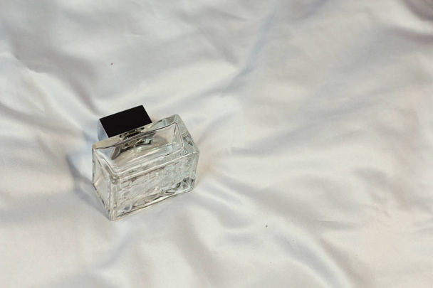 Barna divat divatos palackok parfüm WC víz illatok feküdnek egy ezüst szürke lap az ágyon, felülnézetből. Női és férfi illatok  - Fotó, kép