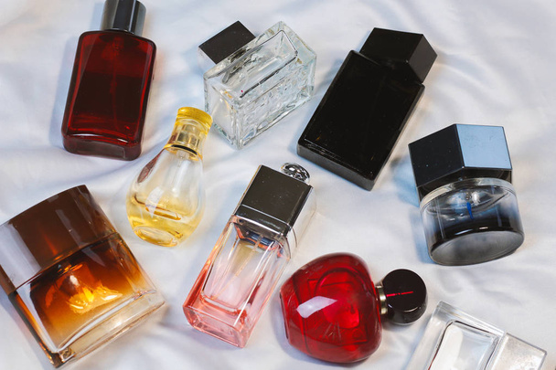 Coloridas botellas de moda de perfume fragancias de agua del inodoro se encuentran en una sábana gris plateado en la cama, vista superior. Fragancias femeninas y masculinas
  - Foto, Imagen