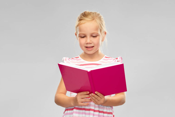 smiling little girl reading book - Zdjęcie, obraz