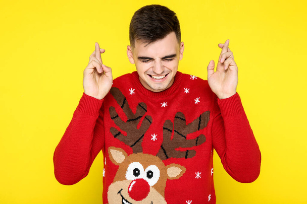 Beautiful man in red christmas sweater on yellow background - Fotó, kép