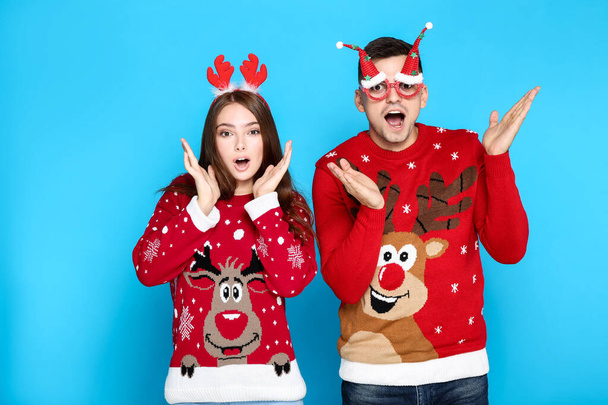 Beautiful man and woman wearing christmas sweaters with red horn - Foto, Imagem