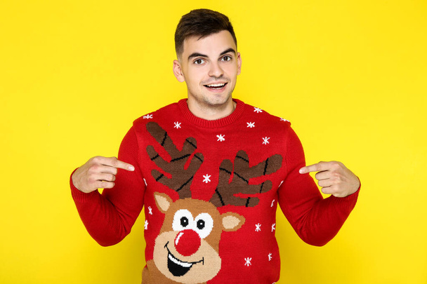 Beautiful man in red christmas sweater on yellow background - Foto, immagini