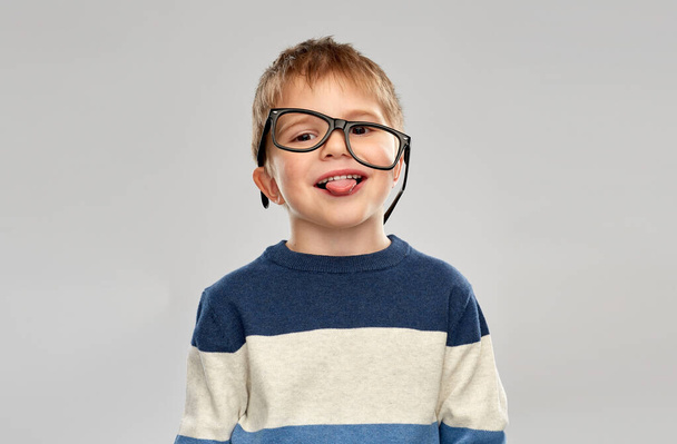 portrait of little boy in glasses showing tongue - Photo, image