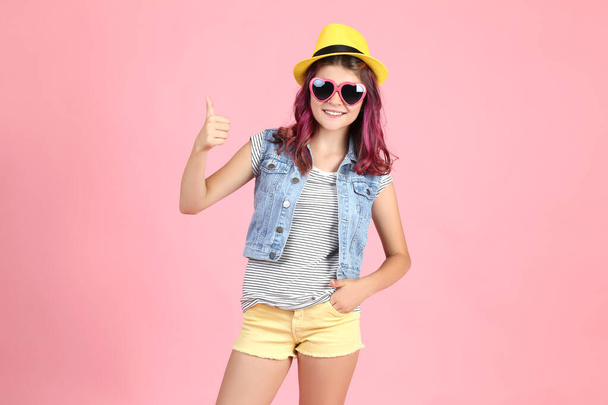 Beautiful young girl in fashion clothing showing thumb up on pin - Photo, Image