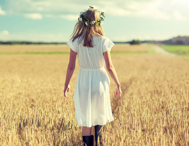 счастливая молодая женщина в цветочном венке на зерновом поле - Фото, изображение