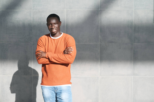 Porträt eines jungen Afrikaners, der die Arme verschränkt und lächelt - Foto, Bild
