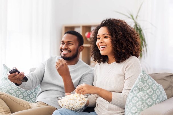 african couple with popcorn watching tv at home - Valokuva, kuva
