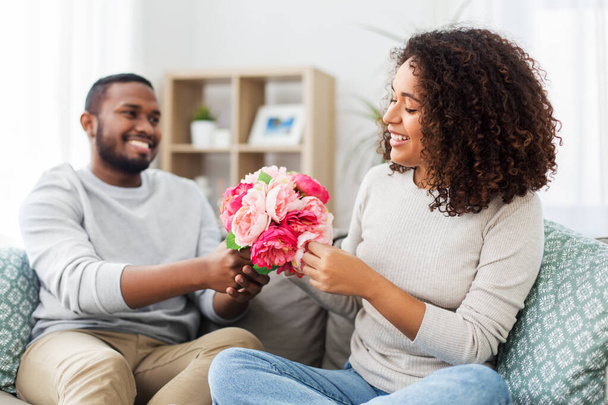 happy couple with bunch of flowers at home - Fotó, kép