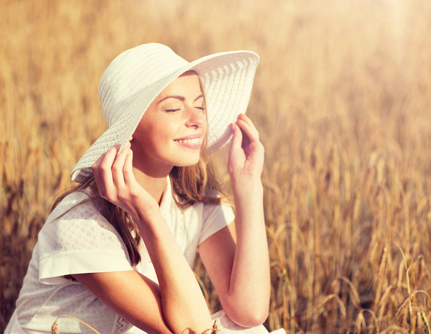 glückliche junge Frau mit Sonnenhut auf einem Getreidefeld - Foto, Bild