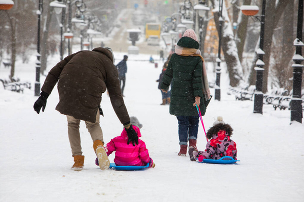dzieci ślizgające się na zimowym wzgórzu w parku miejskim - Zdjęcie, obraz