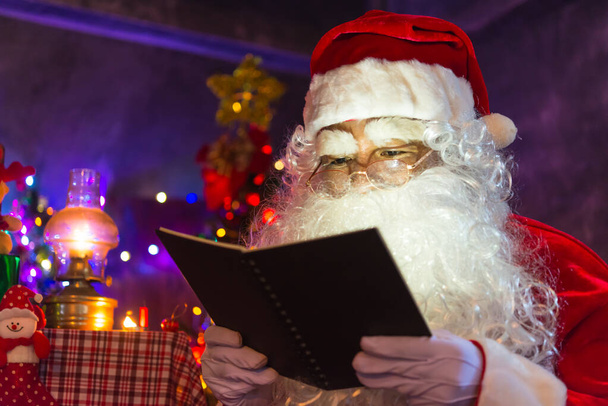 Weihnachtsmann las nachts im Haus ein Buch, das Licht aus dem Buch, mit dem Licht aus dem Laternenzimmer - Foto, Bild