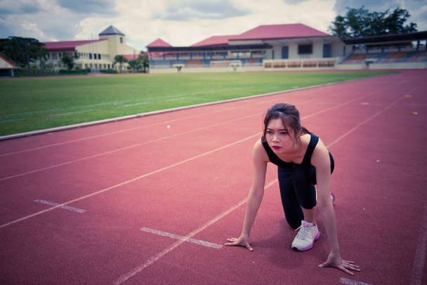 Young asian woman in a position start on a running track - Фото, изображение