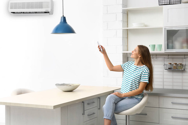 Young woman with air conditioner remote control at home - Photo, Image