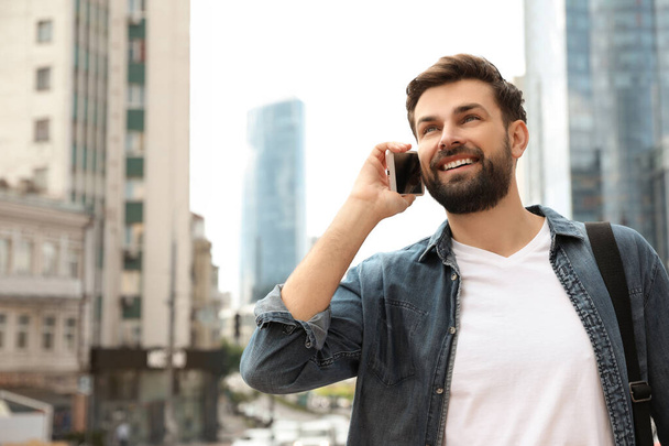 Handsome man talking on phone in modern city - Fotó, kép