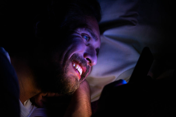 Jovem feliz homem não pode dormir e está assistindo algo em seu ph
 - Foto, Imagem