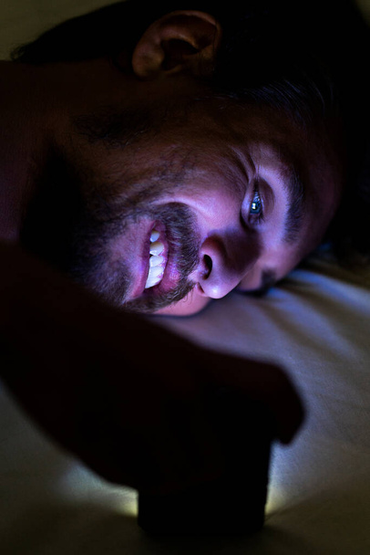 Бородатый счастливый молодой человек лежит в своей постели и улыбается, пока ва
 - Фото, изображение