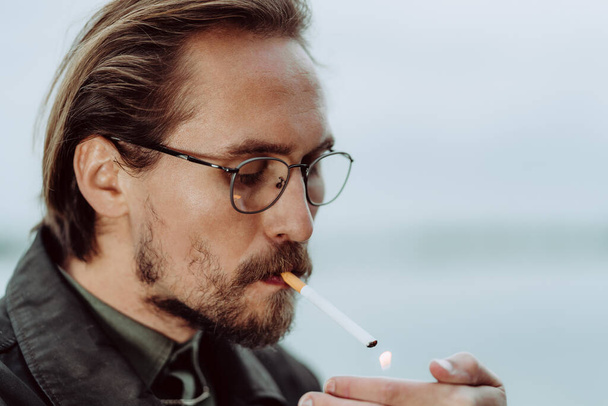 Mladý pohledný muž zapaluje cigaretu - Fotografie, Obrázek