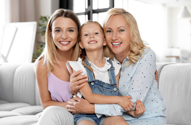 Young woman with mature mother and little daughter in living room - Foto, Imagem