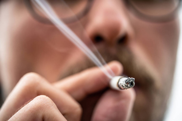 Close-up foto van een jonge man die een sigaret rookt - Foto, afbeelding
