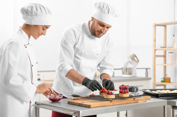 Pastry chefs preparing desserts at table in kitchen - Foto, immagini