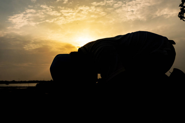 Siluet Genç Asyalı Müslüman adam gün batımında dua ediyor, Ramazan festivali konsepti - Fotoğraf, Görsel