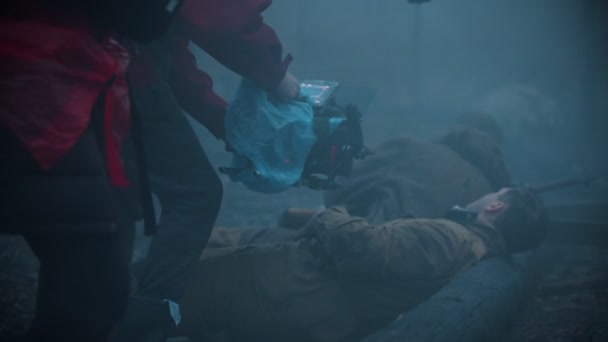 Scena za kulisami - ranni żołnierze leżący na ziemi we mglistym lesie - Materiał filmowy, wideo