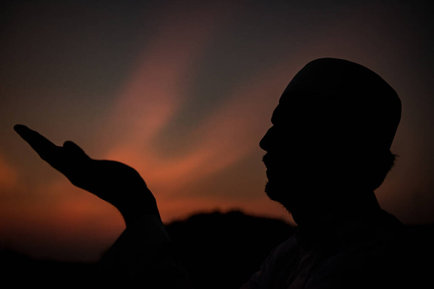 シルエット・ヤング・アジアのイスラム教徒の男性が日没を祈って、ラマダーン祭のコンセプト - 写真・画像