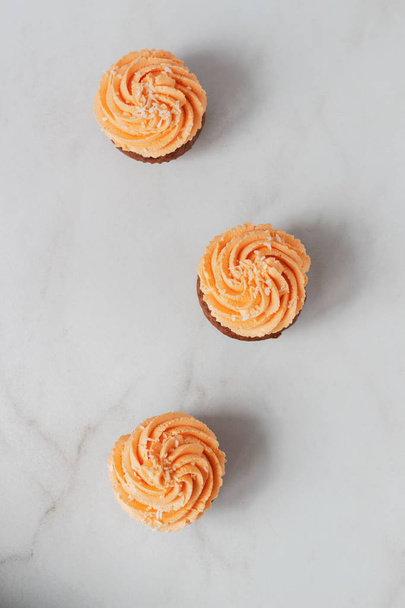 Vista superior de cupcakes set com cobertura laranja no fundo branco
 - Foto, Imagem