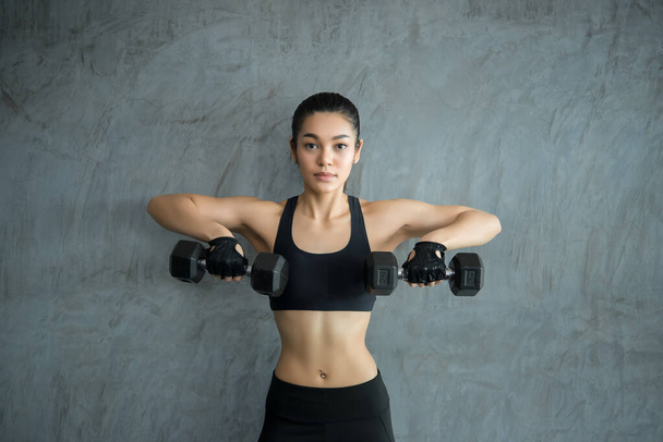 Close up asian beautiful sport girl on wall of gym,Thailand love health,Slim woman workout concept,Lift up dumbell - Foto, Imagen