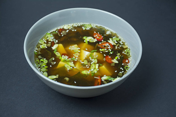 豆腐とハーブのみそ汁。アジア料理暗い背景。テキストのスペース. - 写真・画像