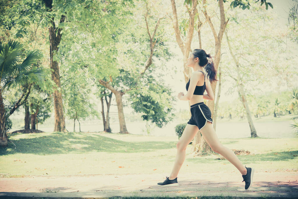 Gyönyörű ázsiai nő kocog az úton éget zsírt a parkban nappal, vékony lány szeretet egészséges magát, kocogás egy gyakorlat, ami úgy érzi, nagyon jó, ő fut, elmosódott mozgás kép - Fotó, kép