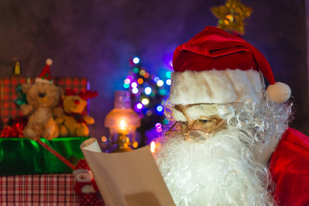 Papá Noel sosteniendo el papel y leerlo, concepto de Feliz Navidad
 - Foto, Imagen