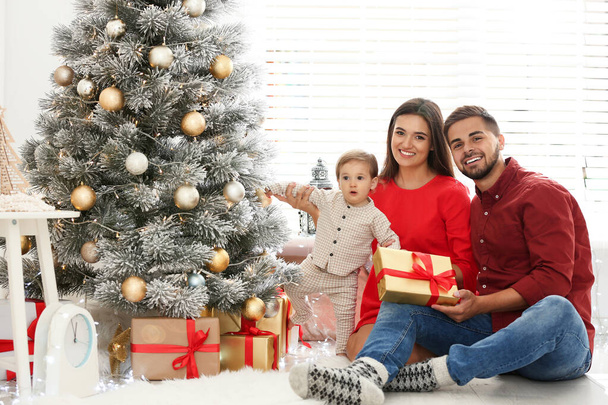 Happy family with cute baby near Christmas tree at home - Foto, imagen