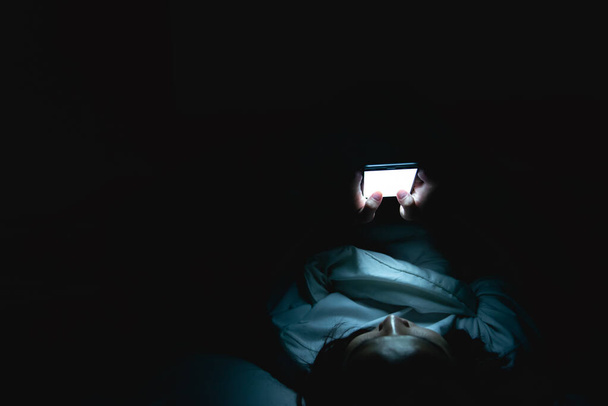 Азиатка играет в игры на смартфоне в постели ночью, Таиланд людей, наркоман социальных медиа
 - Фото, изображение