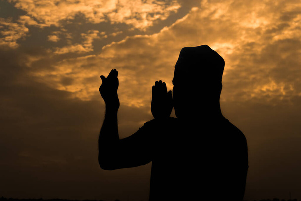 Силует Молодий азійський муслім, що молиться на заході сонця, Рамадан. - Фото, зображення