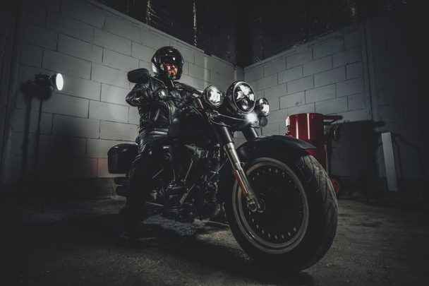 Motocyklista z motocyklem w garażu - Zdjęcie, obraz