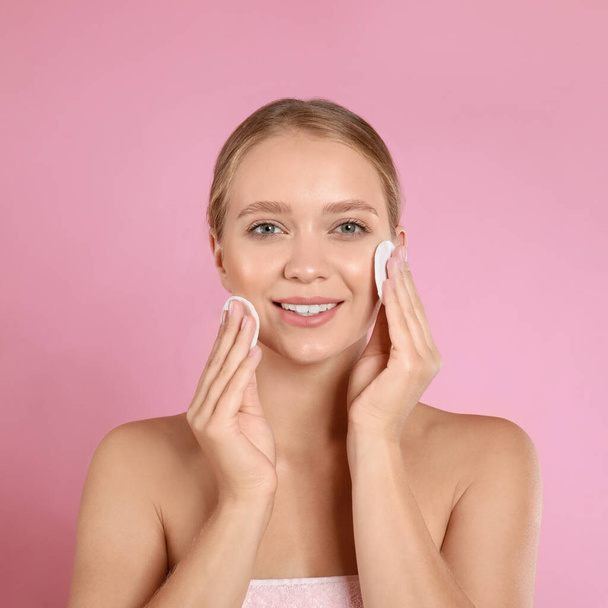 Beautiful young woman with cotton pads on pink background - Foto, afbeelding