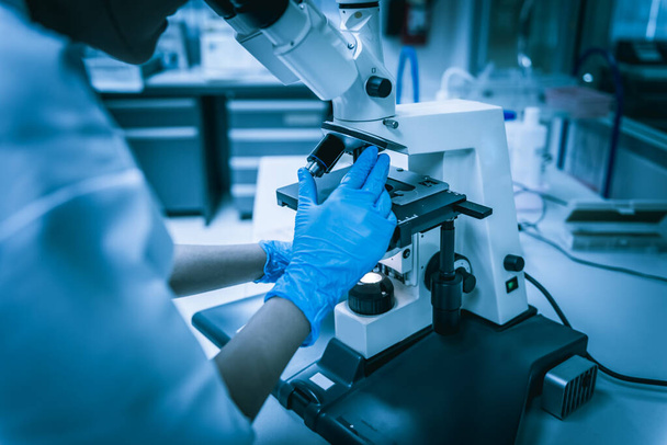junger asiatischer Wissenschaftler beim Blick durch ein Mikroskop in einem Labor.. - Foto, Bild